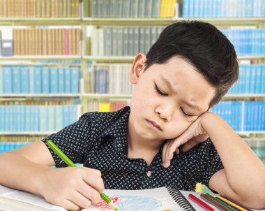 Bir çocuk bir kitaplıktaki ödev memnun değil