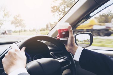 Bir fincan kahve tutarken arabayı kullanan adam