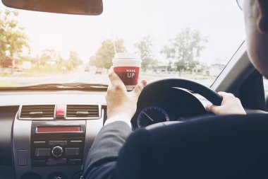 Bir fincan kahve tutarken arabayı kullanan adam