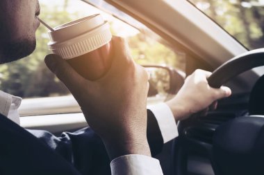 Bir fincan kahve tutarken arabayı kullanan adam