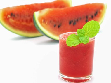 Beyaz zemin üzerine nane bezemeli bir bardak taze karpuz seçici odak