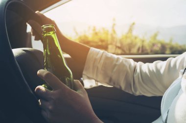 Bir araba sürüş sırasında bira şişesi tutan kadın