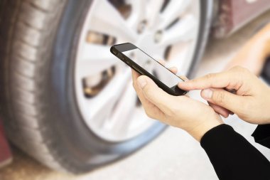 Adam cep telefonu birisi araba lastiği arka plan üzerinde arama kullanarak