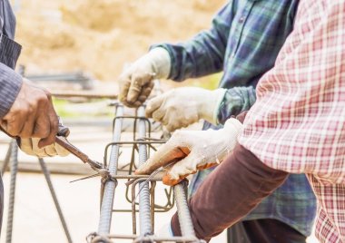 İnşaat işçileri çelik çubuklar betonarme sütununda yüklemekte olduğunuz