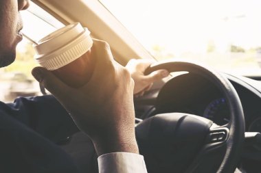 Bir fincan kahve tutarken arabayı kullanan adam