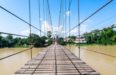 Wat Phra Si Ratana Mahathat, The Si Satchanalai tarihi Park, Si Satchanalai bölge, Sukhothai Eyaleti, Kuzey Tayland, yürüyen bazı insanlarla antik asma köprü