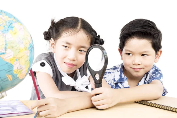 アジアの子供たちは ホワイト バック グラウンドで拡大鏡を使用して世界を勉強しています — ストック写真