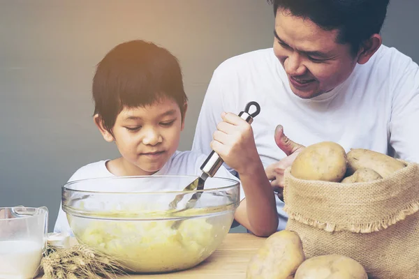 Daddy and son making mashed potatoes happily