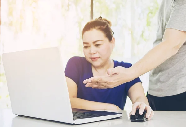 A man is training a woman working with computer in modern office