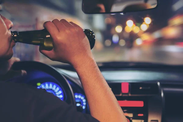 男人喝啤酒 而夜间开车在城市危险 左手驱动系统 — 图库照片