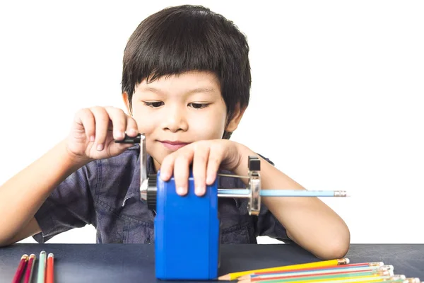 Ένα Αγόρι Είναι Ακόνισμα Του Μολύβι Χρησιμοποιώντας Μηχανική Ξύστρα Λευκό — Φωτογραφία Αρχείου
