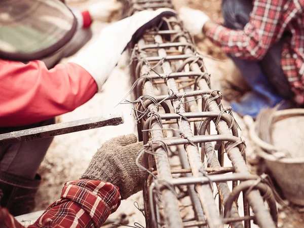 Vintage style photo of construction workers are installing steel rods in reinforced concrete beam