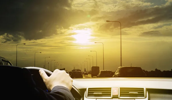 Man is driving a car on sunny day with golden sky and cloud background