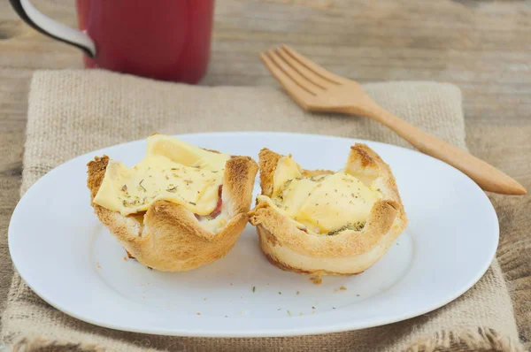 Egg cheese bread toast on white dish with wooden fork and red coffee mug background