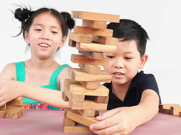 Children playing with wood blocks tower game for practicing their physical and mental skill.