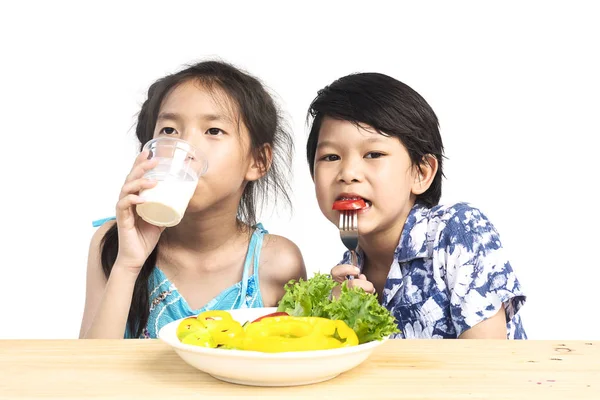 アジアの少年と少女を示す新鮮なカラフルな野菜と白背景に分離した牛乳のガラスを持つ式をお楽しみください — ストック写真