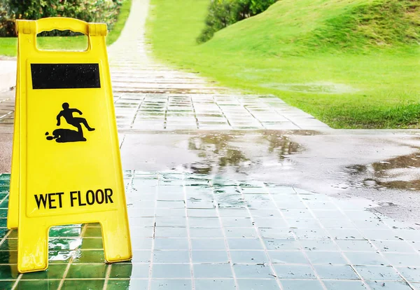 Wet floor caution sign with rain drop on the green tiles floor