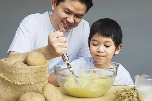 Daddy and son making mashed potatoes happily