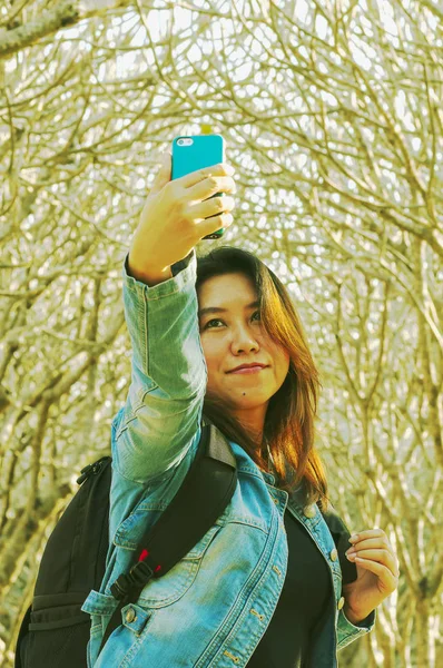 Pumaria ツリー背景を持つ携帯電話を使用して Selfie 写真を撮る若いアジア女性 — ストック写真