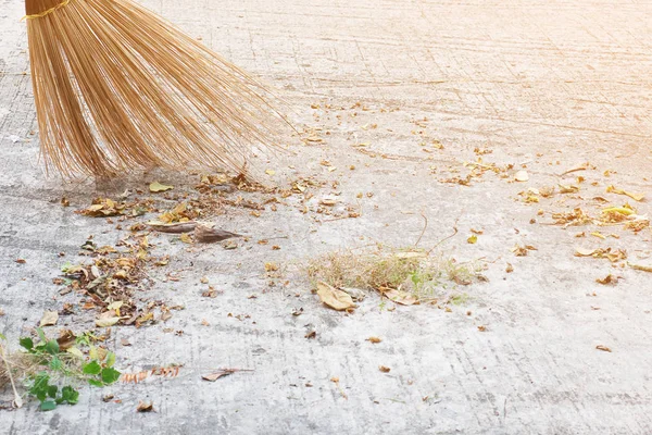 Man cleaning outdoor road using bloom made from dry coconut leave product - local people lifestyle concept in Thailand