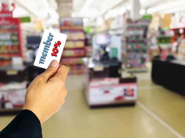 Businessman holding member card discount ten percent overlay on blurred superstore.