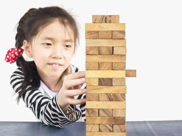 Asian girl playing jenga, wood blocks tower game for practicing physical and mental skill