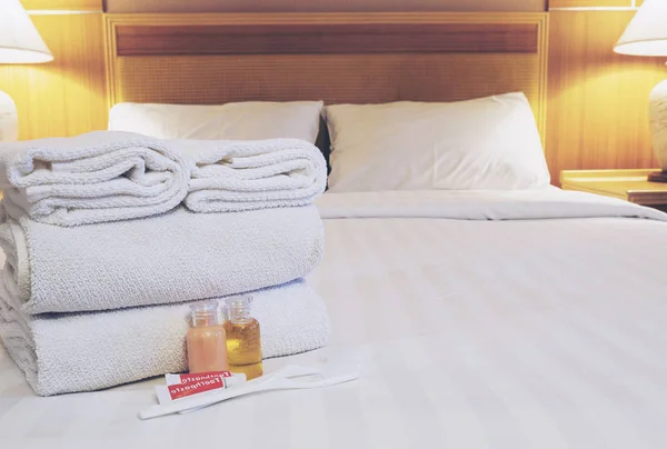 Hotel towel with shampoo and soap bottle set on white bed