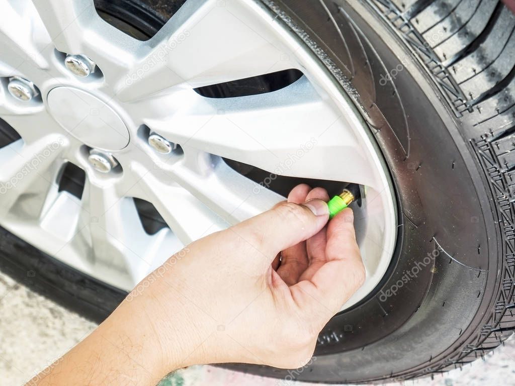 Hand is removing a green tire valve caps for nitrogen tire inflation service