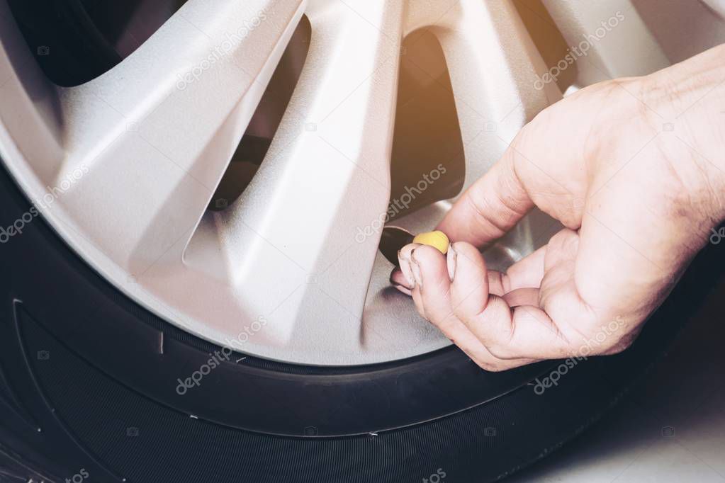 Hand is removing a green tire valve caps for nitrogen tire inflation service - car maintenance safety transportation concept