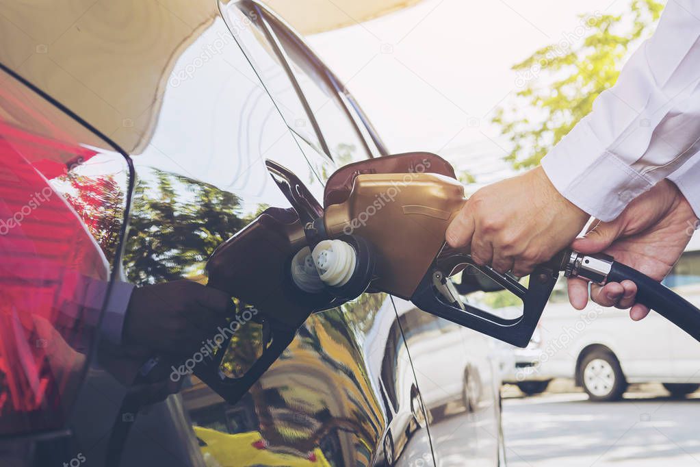 Man putting gasoline fuel into his car in a pump gas station