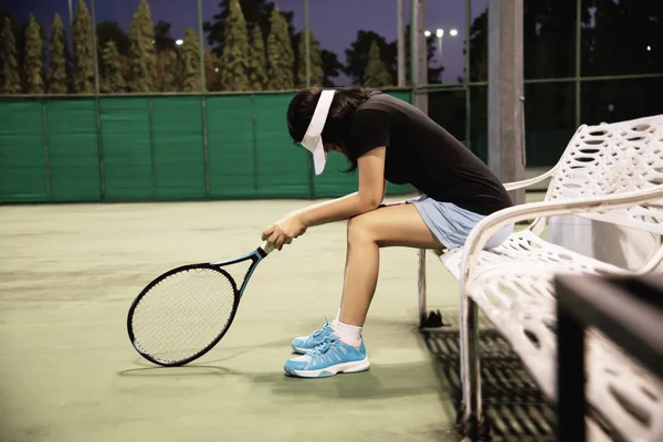 Sad lady tennis player sitting in the court after lose a match - people in sport tennis game concept