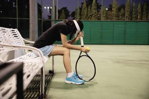 Sad lady tennis player sitting in the court after lose a match - people in sport tennis game concept