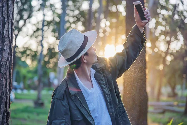 Asian man with mobile phone in forest tree nature - people in spring nature and technology concept