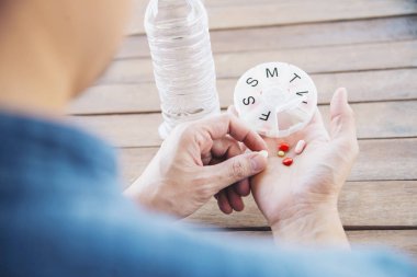 People prepare daily medicine tablet in pillbox - people healthcare with medicine pills concept clipart