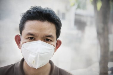 Maske takan adam hava kirliliği ortamında ince tozları korur - hava kirliliği konsepti için koruma ekipmanı olan kişiler