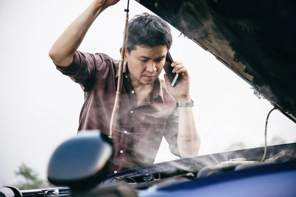 Man try to fix a car engine problem on a local road Chiang mai Thailand - people with car problem transportation concept