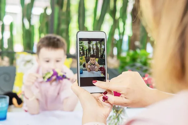 Mom use mobile phone take a photo of her son in restaurant - family lifestyle mother and son enjoy moment concept