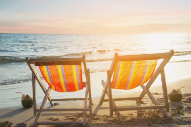 Sıcak günbatımı ile kum plajda Çift dinlenmek sandalye - güzel deniz doğa konsepti tatil