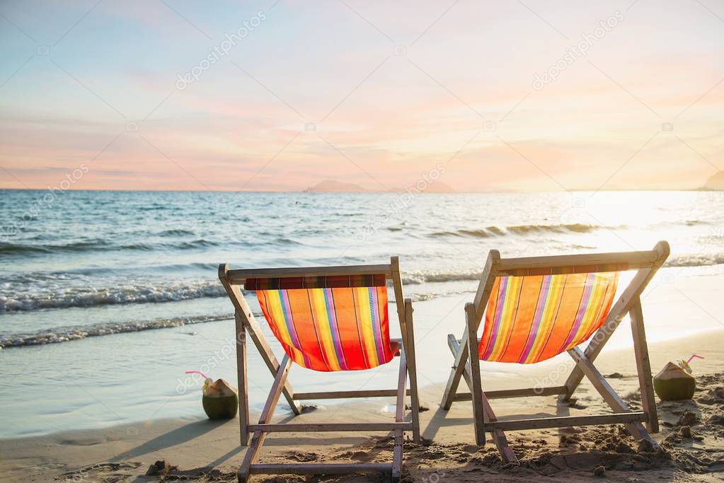 Couple relax chair on sand beach with warm sunset - vacation in beautiful sea nature concept 