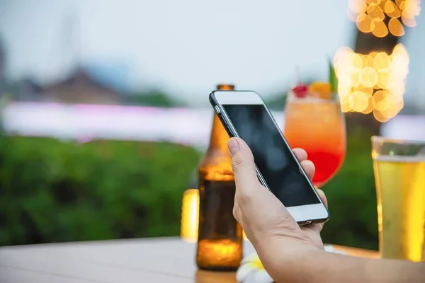 Man using mobile during happy time relax in restaurant with softdrink and green garden background - people relax with technology lifestyle concept