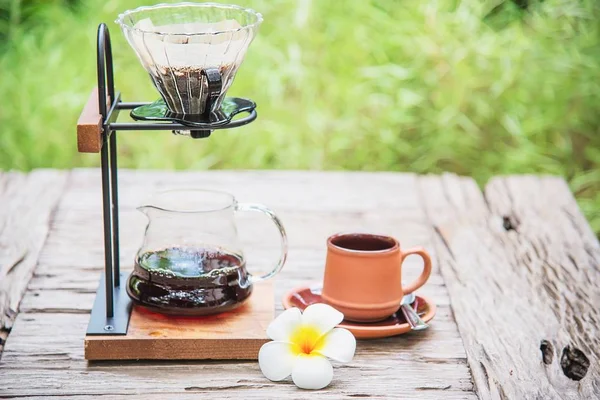 Making drip coffee in vintage coffee shop with green garden nature background - fresh coffee in nature concept