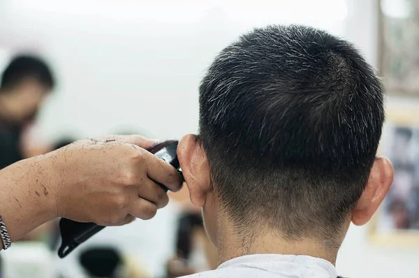 Man is cut his hair in barber shop - people in hairdresser beauty salon concept