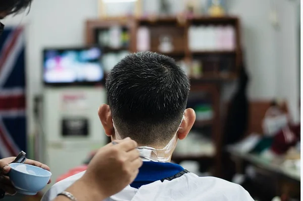 Man is cut his hair in barber shop - people in hairdresser beauty salon concept