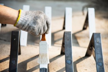 İnsan, çelik mobilya parçası için beyaz renk boyuyor. İş konseptinde ressam.