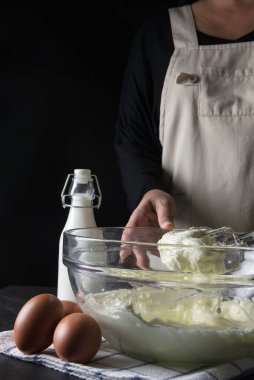 Siyah arka planda kremalı pasta yapan kadın.