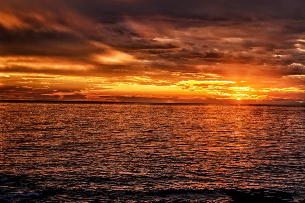 Puesta de sol roja con cielo nublado junto al mar — Foto de Stock