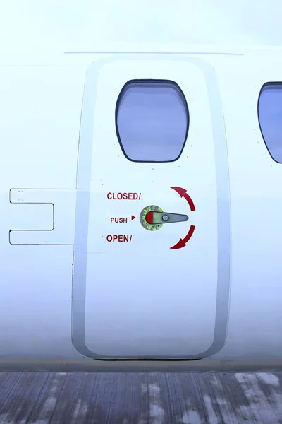 Entry door of small white business jet with red signs