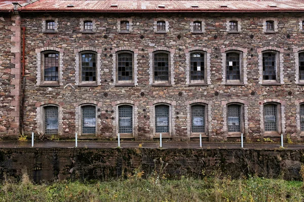 Alte ungenutzte Fabrikhausfassade mit vielen kaputten Fenstern — Stockfoto