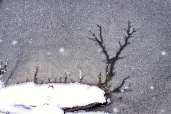 Расколотый лед на озере с заснеженным камнем — стоковое фото