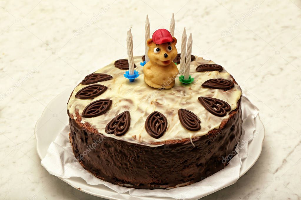 Chocolate cake with ornaments and little teddy bear marzipan figure with candles